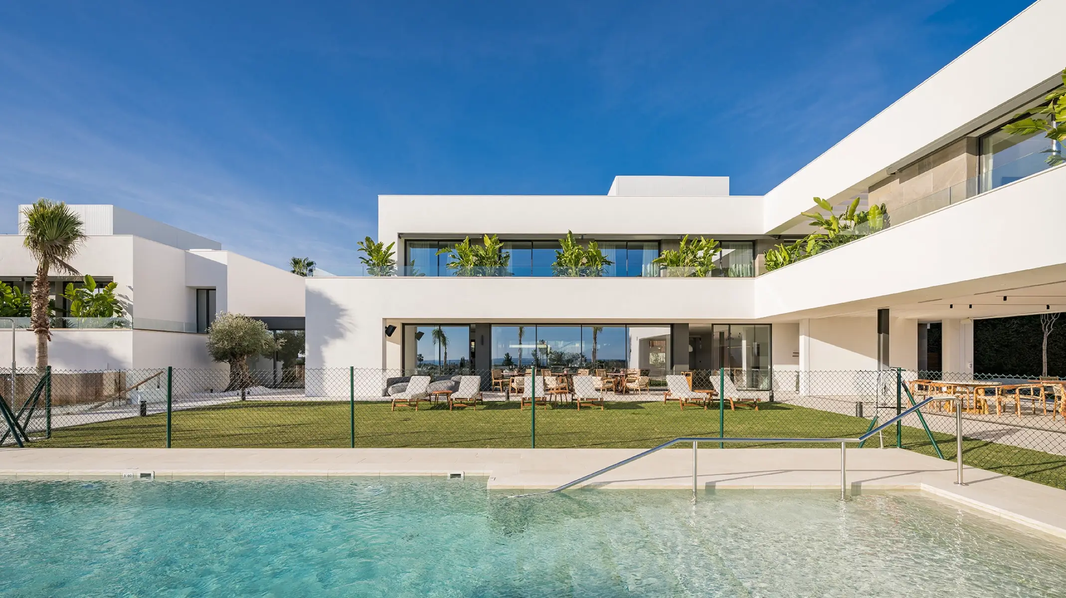 Exterior del santuario de recuperación Naghoi — piscina, jardines y arquitectura blanca moderna en Estepona, España.
